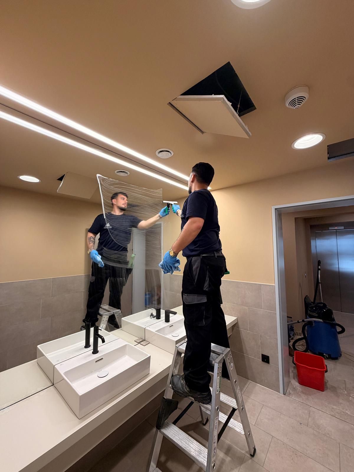 Mitarbeiter bei der professionellen Reinigung einer großen Spiegelfläche